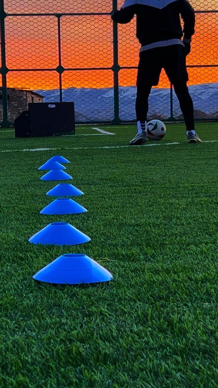 Cones azuis alinhados em campo ao pôr do sol